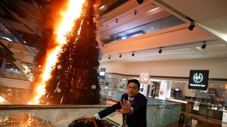 Un homme tente d'éteindre un arbre de Noël en feu au centre commercial Festival Walk à Kowloon Tong, Hong Kong