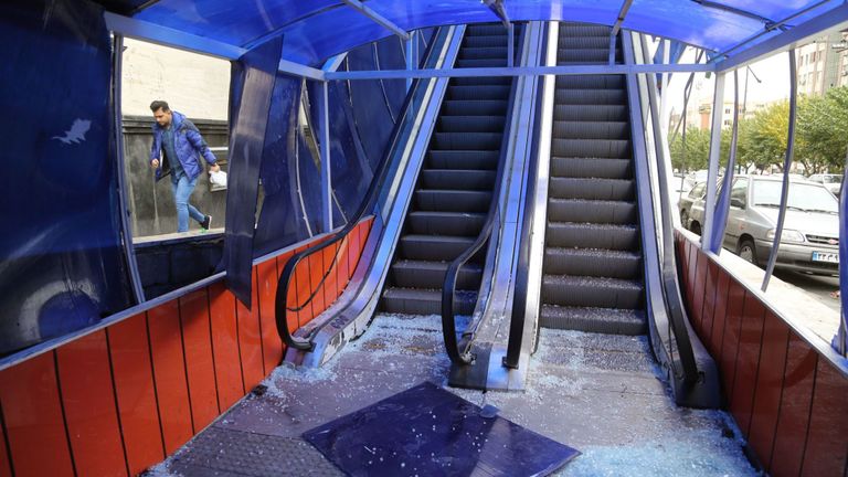 Un homme passe à l'entrée d'un passage piétonnier qui a été vandalisé par des manifestants à Téhéran. 