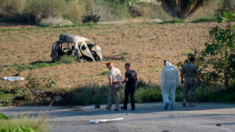 La police et des experts médico-légaux inspectent l'épave d'une voiture piégée qui aurait tué le journaliste d'investigation