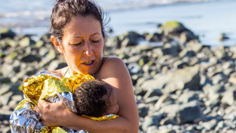 Un enfant migrant est retenu par un passionné de plage après que des migrants ont atterri sur un canot à la plage d'Aguila, sur l'île de Grande Canarie, en Espagne, le 29 novembre 2019. REUTERS / Borja Suarez REFILE - LOCALISATION CORRECTIONNELLE