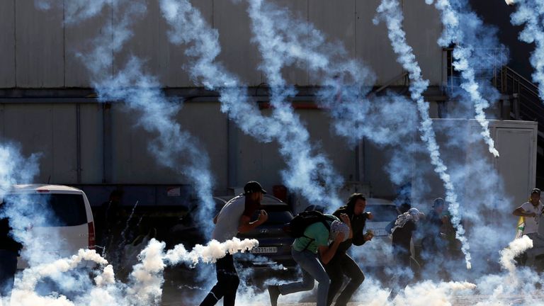 Des jeunes Palestiniens s'enfuient à cause de la fumée de gaz lacrymogène tirée par les forces de sécurité israéliennes 