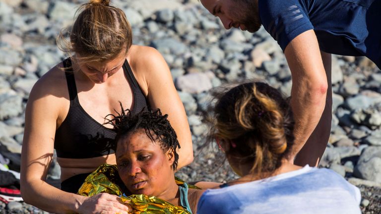 Un passionné de plage assiste un migrant après qu'un groupe dans un canot a atterri sur la plage d'Aguila, sur l'île de Gran Canaria, en Espagne, le 29 novembre 2019. REUTERS / Borja Suarez REFILE - LOCALISATION CORRECTION