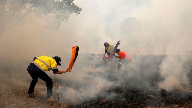 Des habitants tentent de supprimer les incendies, d'un feu de brousse, en se dirigeant vers une maison située sur une propriété à Koorainghat, près de Taree, dans la région de la côte nord du NSW, en Australie, le 12 novembre 2019.