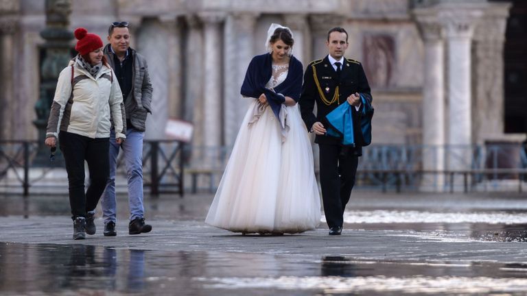 Un couple de jeunes mariés traverse une place inondée dans la ville lagon
