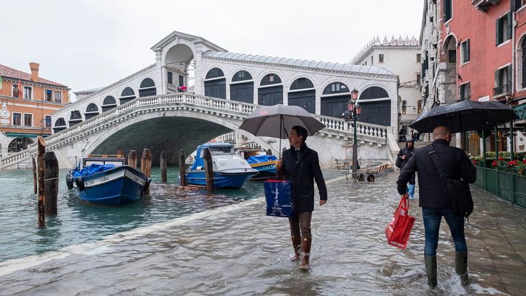 Les touristes marchent dans les hautes eaux près du pont du Rialto sur la Piazza San Marco le 12 novembre 2019 à Venise, Italie