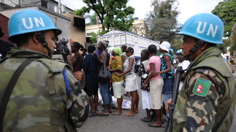 Des soldats de l'ONU surveillent la distribution de nourriture le 11 février 2010 aux femmes de la ville de Pétion-ville, une banlieue de Port au Prince. Les forces européennes fourniront un abri d'urgence à certaines des 90 000 personnes toujours sans domicile en Haïti un mois après un séisme massif, a déclaré jeudi la chef des Affaires étrangères de l'UE, Catherine Ashton. AFP PHOTO Thony BELIZAIRE (Le crédit photo doit se lire THONY BELIZAIRE / AFP via Getty Images)