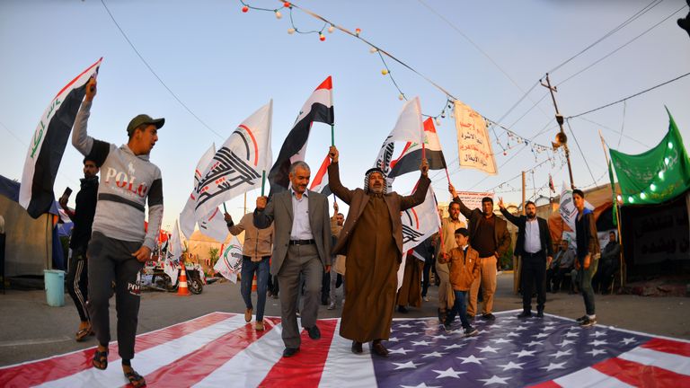 Les Irakiens marchent sur un drapeau national américain le 30 décembre 2019, lors d'une manifestation pour dénoncer les attaques de la nuit précédente par des avions américains sur plusieurs bases appartenant aux brigades du Hezbollah près d'Al-Qaim, un district irakien limitrophe de la Syrie. - Les frappes aériennes américaines contre un groupe pro-iranien en Irak auraient tué au moins 25 combattants, déclenchant la colère dans un pays pris dans les tensions croissantes entre Téhéran et Washington. (Photo de Haidar HAMDANI / AFP) (Photo de HAIDAR HAMDANI / AFP via Getty Images)