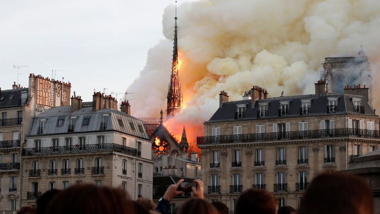 Les spectateurs sont sous le choc alors que la flèche au sommet de la cathédrale Notre-Dame s'effondre dans un incendie.