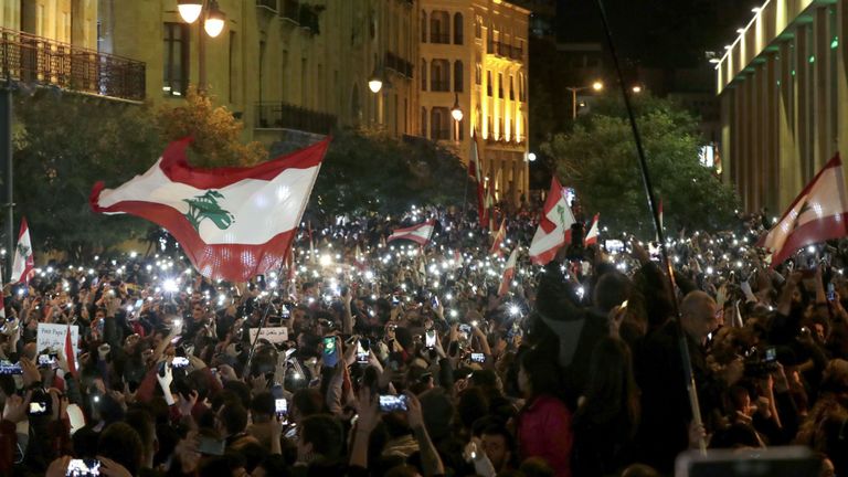 Des manifestants libanais utilisent leurs lumières de téléphone lors d'une manifestation anti-gouvernementale dimanche 