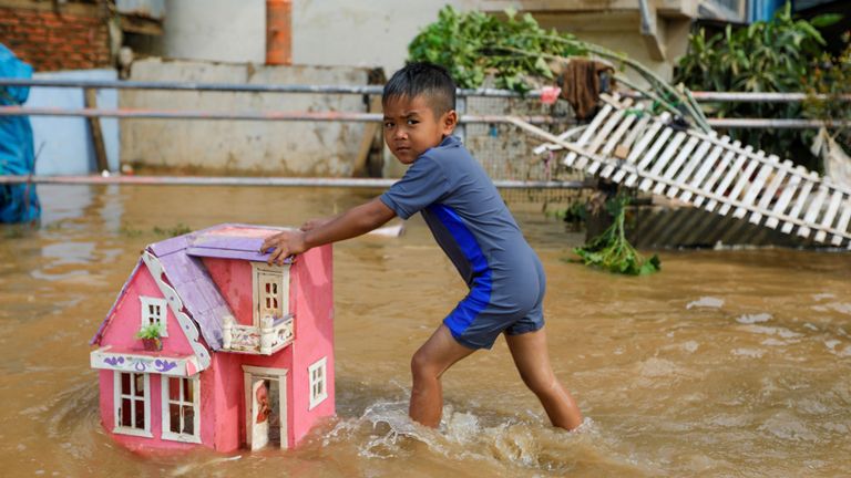 Un garçon pousse une maison de jouets dans les eaux de crue après de fortes pluies à Jakarta, Indonésie