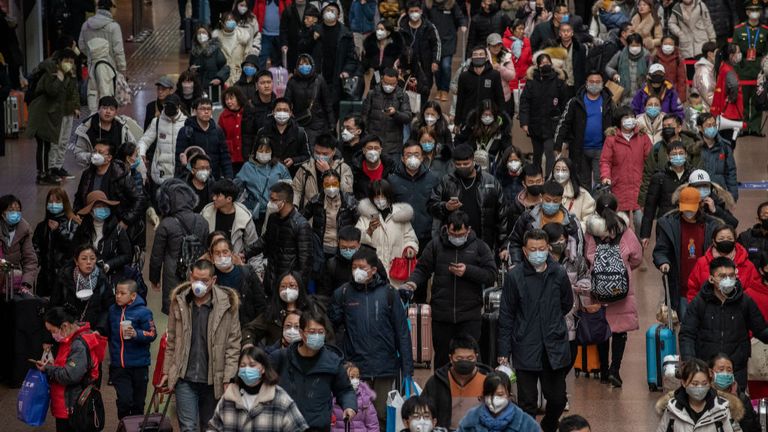 Les passagers chinois, la plupart portant des masques, arrivent à bord des trains avant la fête annuelle du printemps dans une gare de Pékin 