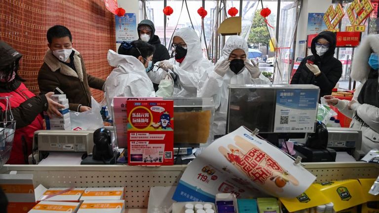 Des employés de pharmacie portant des vêtements et des masques de protection servent des clients à Wuhan 