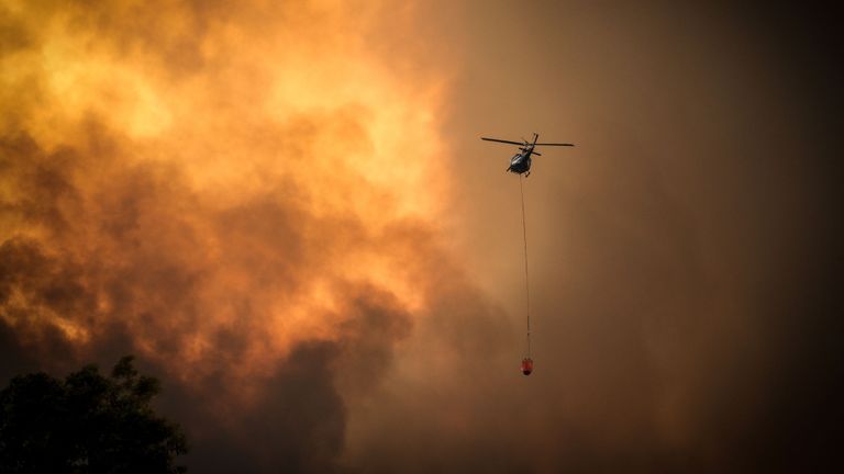Des hélicoptères déversent de l'eau sur des feux de brousse à l'approche de maisons situées à la périphérie de la ville de Bargo le 21 décembre 2019 à Sydney, Australie