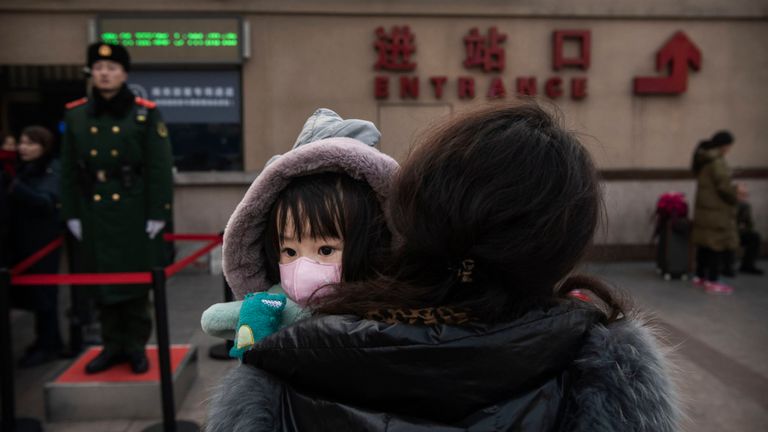 Une fille porte un masque de protection en attendant de monter à bord d'un train à Pékin