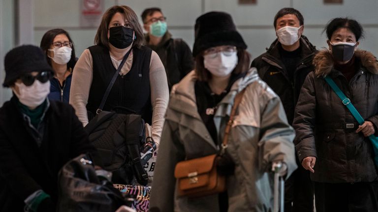 Les passagers portent des masques de protection à leur arrivée à l'aéroport de Beijing Capital