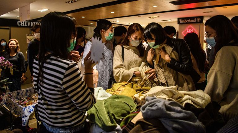 Sur cette photo prise le 23 janvier 2020, des acheteurs portant des masques protecteurs parcourent des vêtements sur un étal installé dans le cadre d'un marché du Nouvel An lunaire sur le thème de la démocratie dans un centre commercial à Hong Kong