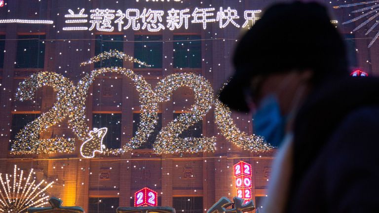 Une femme marche devant un signe du Nouvel An à Wangfujing le 26 janvier 2020 à Pékin, Chine