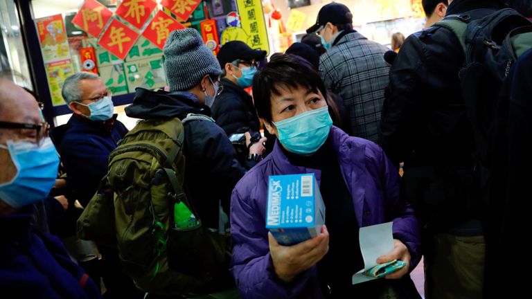Une femme s'accroche à une boîte de masques après avoir fait la queue à Hong Kong