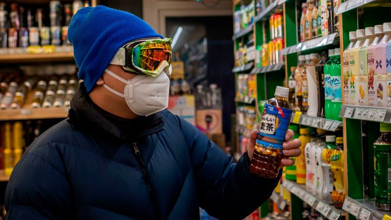 Un homme portant un masque de protection, des lunettes et des gants dans un supermarché de Pékin