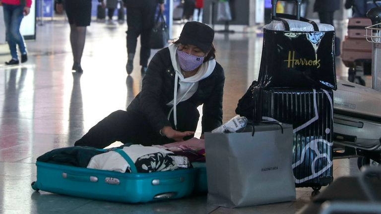 Une femme portant un masque facial fait sa valise dans la zone des départs du terminal 5 de l'aéroport d'Heathrow