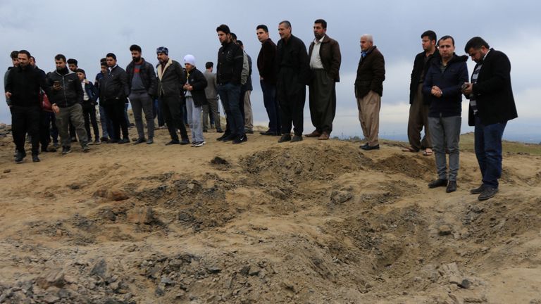 Des hommes regardent un cratère provoqué par un missile tiré par l'Iran sur les forces de la coalition dirigée par les États-Unis à Duhok, en Irak 