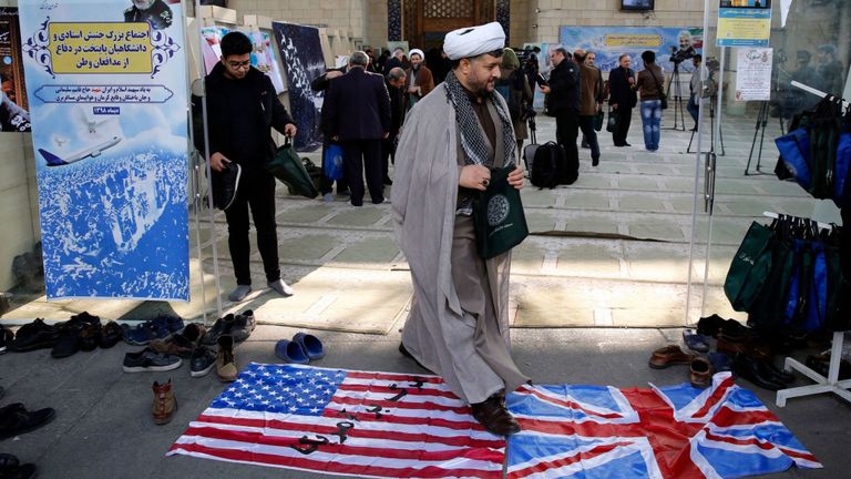 Un religieux iranien marchant sur des drapeaux britanniques et américains Pic: Shutterstock
