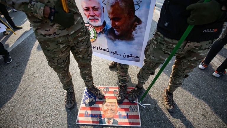 Les manifestants se tiennent sur un drapeau américain de fortune portant une caricature du président Donald Trump
