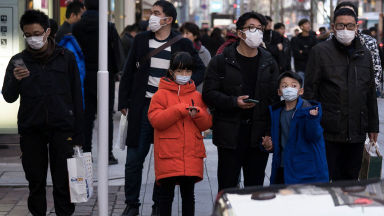Les touristes chinois portant des masques traversent le quartier commerçant de Ginza à Tokyo, Japon