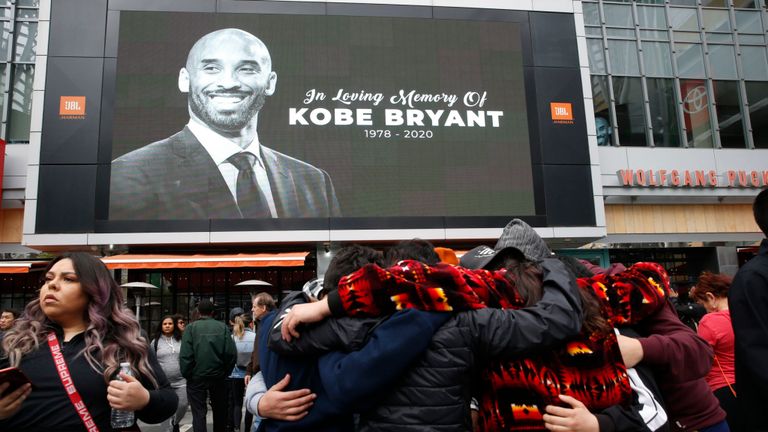 Les fans se rassemblent près d'une image de Kobe Bryant affichée sur un grand écran à l'extérieur du Staples Center, LA