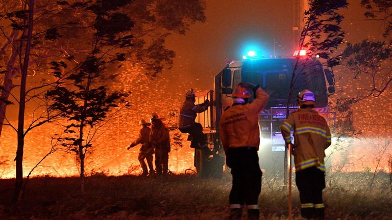 Les pompiers arrosent les arbres alors qu'ils luttent contre les feux de brousse autour de la ville de Nowra dans l'État australien de la Nouvelle-Galles du Sud le 31 décembre 2019