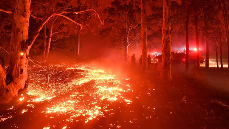 Des braises brûlantes couvrent le sol alors que les pompiers (à l'arrière R) luttent contre les feux de brousse autour de la ville de Nowra dans l'État australien de la Nouvelle-Galles du Sud le 31 décembre 2019