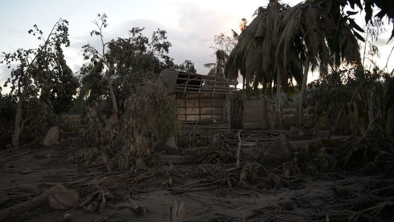 Une vue générale d'une maison détruite et d'arbres recouverts de boue après l'éruption