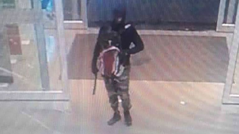 Suspect portant une cagoule, un pantalon de camouflage et portant une arme de poing avec un suppresseur attaché, alors qu'ils arrivent pour voler un magasin d'or à l'intérieur d'un grand magasin dans la province de Lopburi, Thaïlande