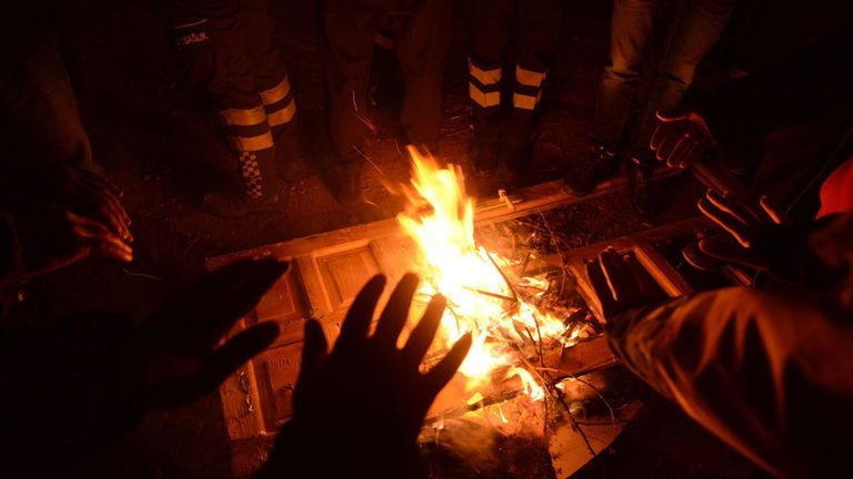 Les autorités et la police turques tentent de se réchauffer sur les lieux d'un immeuble effondré