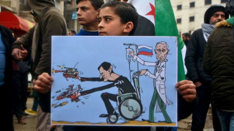 Un jeune syrien est titulaire d'une caricature du président syrien Bachar al Assad et du président russe Vladimir Poutine lors d'une manifestation dans la ville d'Idlib