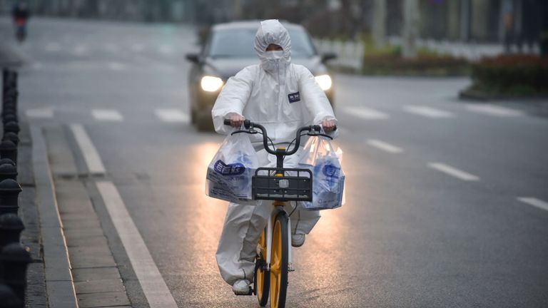 Cette photo prise le 27 février 2020 montre un résident portant une combinaison de protection à vélo à Wuhan dans la province centrale du Hubei en Chine. - La Chine a signalé 44 décès supplémentaires dus à la nouvelle épidémie de coronavirus le 28 février et 327 nouveaux cas, le chiffre quotidien le plus bas de nouvelles infections en plus d'un mois. (Photo par STR / AFP) / China OUT (Photo par STR / AFP via Getty Images)