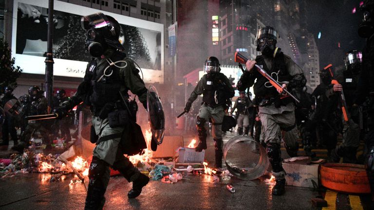 TOPSHOT - La police a passé devant les débris incendiés par des manifestants dans la région de Causeway Bay à Hong Kong le 31 août 2019, alors que les gens manifestent, défiant l'interdiction de se rallier - et les menaces croissantes de la Chine - de descendre dans la rue pour un 13e week-end droit. (Photo par Anthony WALLACE / AFP) (Le crédit photo doit se lire ANTHONY WALLACE / AFP via Getty Images)