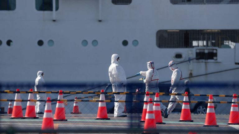 Des travailleurs en tenue de protection sont vus près du Diamond Princess à Yokohama