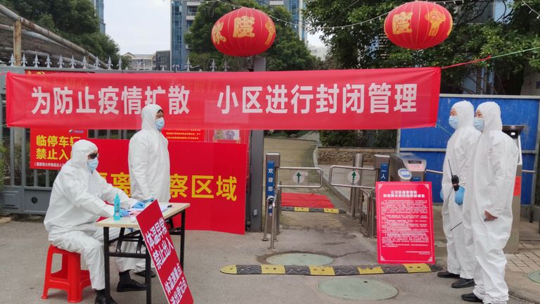 Les travailleurs en tenue de protection enregistrent les résidents et prennent leur température dans un lotissement à Wuhan