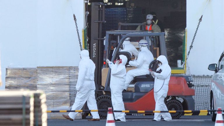 Le personnel vêtu de combinaisons de protection blanches charge des fournitures de secours pour les passagers à bord du bateau de croisière Diamond Princess au terminal de croisière de la jetée de Daikoku dans le port de Yokohama le 6 février 2020. - Dix autres personnes sur un bateau de croisière au large des côtes du Japon ont été testées positives pour le nouveau coronavirus, a annoncé le ministre de la Santé le 6 février, portant le nombre d'infections détectées sur le bateau à 20. (Photo STR / JIJI PRESS / AFP) / Japan OUT (Photo STR / JIJI PRESS / AFP via Getty Images)

