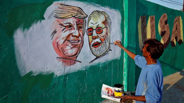 Un homme peignant une photo de Donald Trump et Narendra Modi le long de l'itinéraire que les deux hommes emprunteront