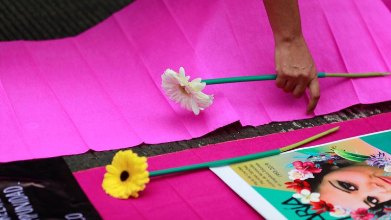 Un manifestant dépose des fleurs sur une affiche lors d'une manifestation contre la violence sexiste au centre-ville de Mexico, Mexique, le 14 février 2020