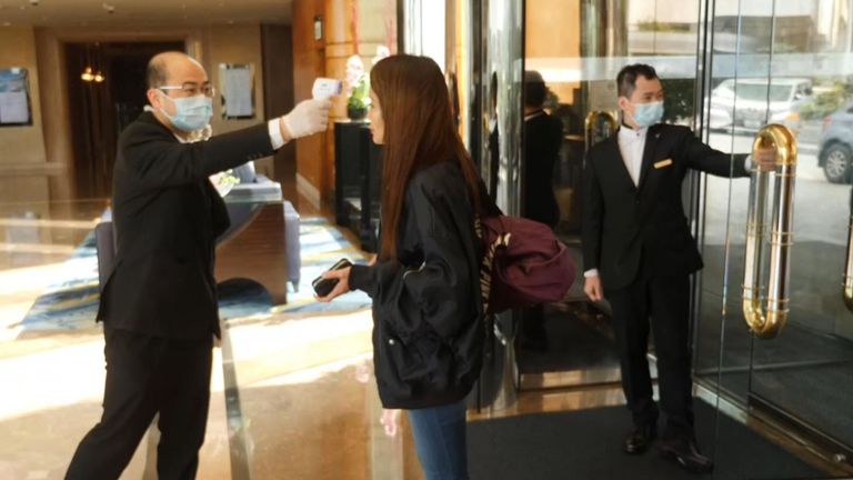 Une femme fait vérifier sa température en entrant dans un hôtel à Hong Kong