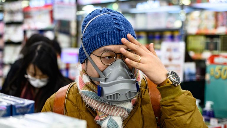 Un homme est vu avec son visage couvert lors de l'achat de paquets de masques dans une pharmacie de Hong Kong 