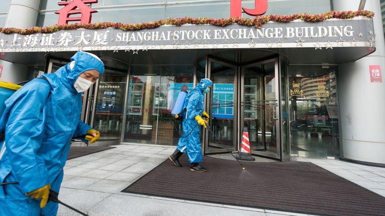 Les travailleurs médicaux pulvérisent un antiseptique à l'extérieur de la porte principale de la Bourse de Shanghai