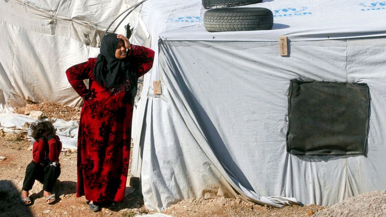 Une réfugiée syrienne se tient devant une tente dans un camp à Bar Elias