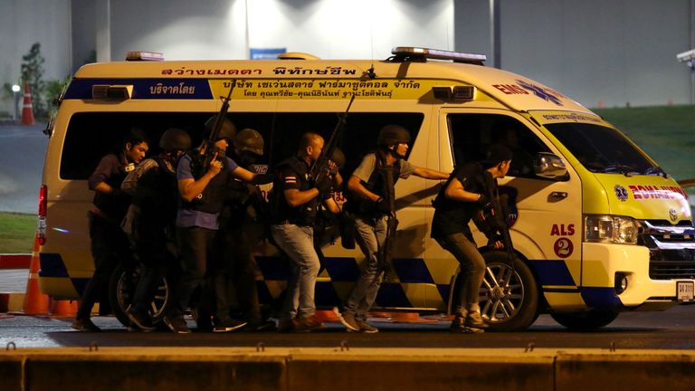 Les forces de sécurité thaïlandaises se cachent derrière une ambulance pour chasser le suspect