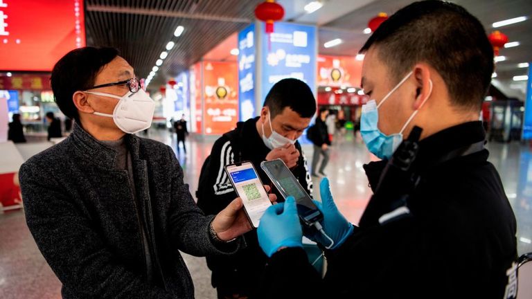 Cette photo prise le 28 février 2020 montre un passager portant un masque facial alors qu'il montre un code QR vert sur son téléphone pour montrer son état de santé à la sécurité à son arrivée à la gare de Wenzhou à Wenzhou. - La Commission nationale de la santé a signalé le 1er mars 573 nouvelles infections, portant le nombre total de cas en Chine continentale à 79 824. (Photo de NOEL CELIS / AFP) (Photo de NOEL CELIS / AFP via Getty Images)
