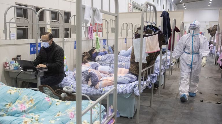 TOPSHOT - Cette photo prise le 17 février 2020 montre un homme (L) qui a présenté des symptômes bénins du coronavirus COVID-19 à l'aide d'un ordinateur portable dans un centre d'exposition transformé en hôpital à Wuhan en Chine dans la province centrale du Hubei. - Le bilan des décès dus à l'épidémie de coronavirus COVID-19 est passé à 1 868 en Chine le 18 février après la mort de 98 personnes supplémentaires, selon la Commission nationale de la santé. (Photo par STR / AFP) / China OUT (Photo par STR / AFP via Getty Images)