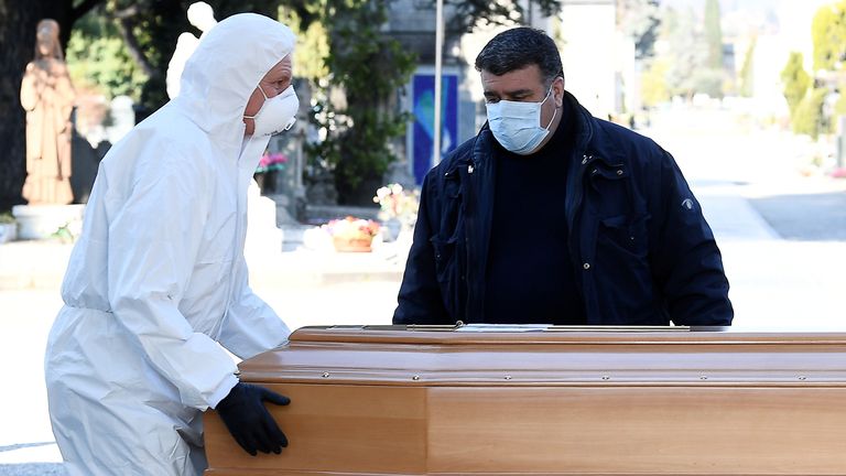 Des travailleurs transportent un cercueil dans un cimetière